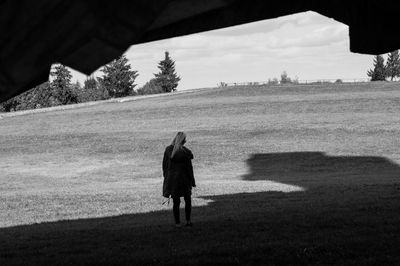 Rear view of woman walking on field against sky