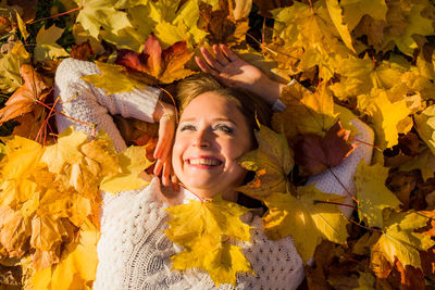 Portrait of smiling young woman with yellow leaves during autumn