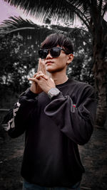 Portrait of young man wearing sunglasses standing outdoors