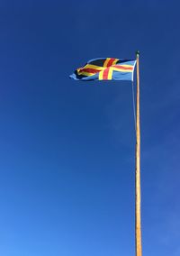 Low angle view of waving flag against clear blue sky