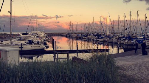 Boats moored at harbor against sky during sunset