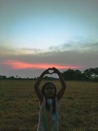 Full length of girl standing on field against sky during sunset