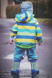 Rear view of boy walking on road