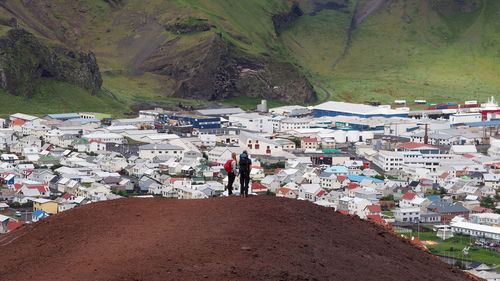 Rear view of people looking at houses in town while standing on mountain