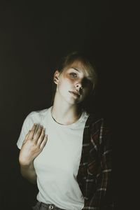 Portrait of beautiful young woman against black background