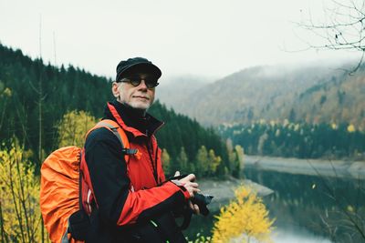 Portrait of man standing by lake against mountains