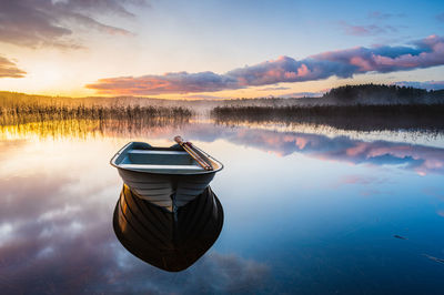 Boat on still lake at sunrise, sweden.