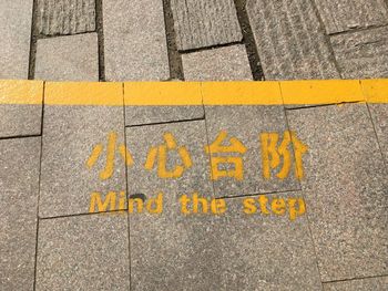 High angle view of yellow text on footpath