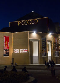 Information sign on street against building at night