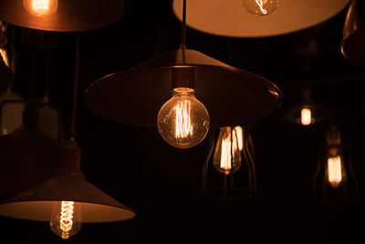 Close-up of illuminated light bulb hanging at home