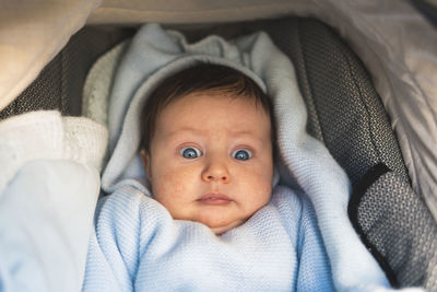 Surprised baby boy lying in pram