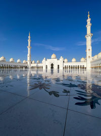 Sheikh zayed grand mosque's stunning reflection on tile with blue sky 