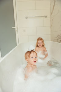 Little brother and sister bathing in a foam bath