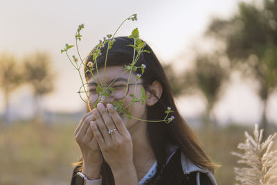 Young woman smelling plant standing outdoors