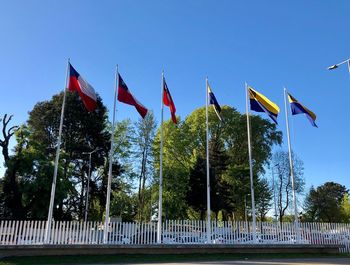 Low angle view of flags against clear blue sky