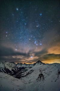 Scenic view of snowcapped mountains against sky at night