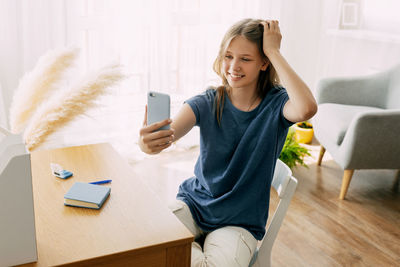 Young woman using digital tablet while sitting on sofa at home