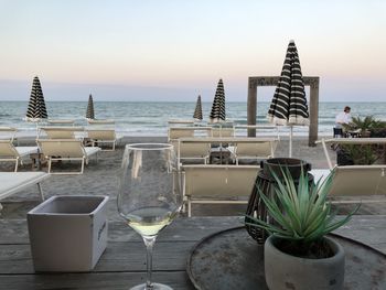 Chairs and tables at beach against clear sky