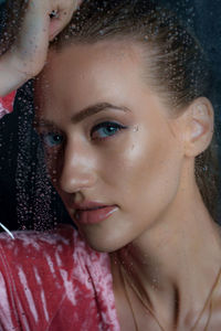 Close-up portrait of beautiful woman with blue eyes seen through window