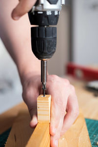 Drive a screw into wood with an electric screwdriver. the theme of craft and woodworking