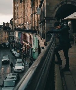 Man standing on railroad tracks by buildings in city