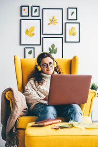 Young woman using laptop while sitting on sofa at home