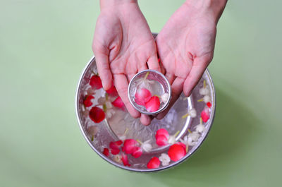 Cropped hands with water and flowers in bowl on table