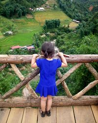 Rear view of woman standing on wooden railing