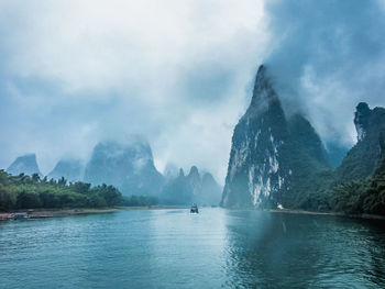 Scenic view of sea by mountains against sky