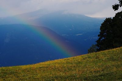 Scenic view of rainbow over mountains against sky