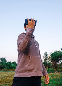 Rear view of man standing on field against clear sky