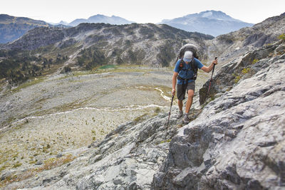 Backpacker hikes across talus slope in mountains near whistler.