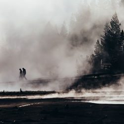 Silhouette people walking at hot spring against trees