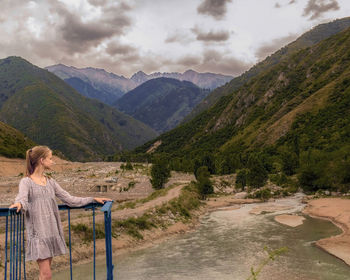 Rear view of woman looking at mountains against sky