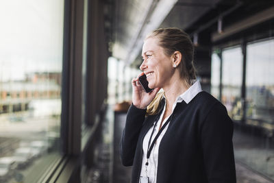 Smiling entrepreneur talking on mobile phone while standing at workplace