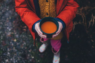 Low section of girl holding drink in container