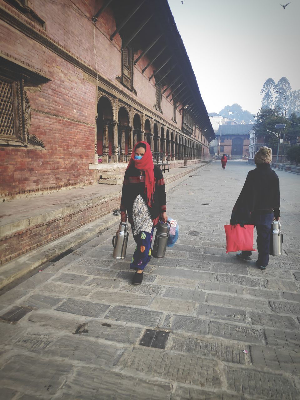 REAR VIEW OF PEOPLE WALKING ON STREET AGAINST BUILDINGS