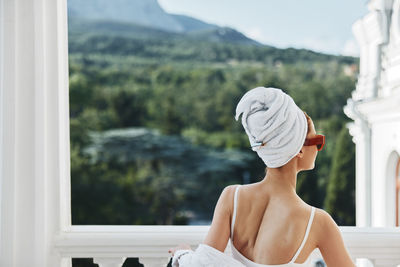 Rear view of woman looking through window