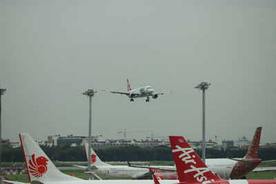 Airplane flying over airport runway against sky