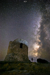 Man standing on rock against sky at night