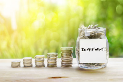 Close-up of coins with investment jar on table outdoors