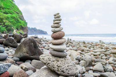 Stack of stones at beach against sky