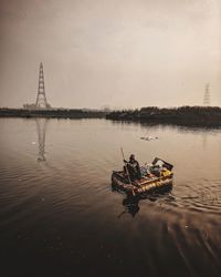 Man sitting in boat at river against sky