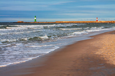 Lighthouse on beach against sky