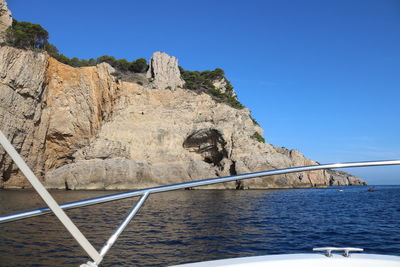 Rock formations by sea against clear blue sky