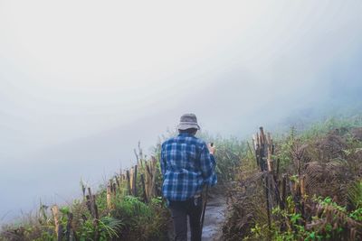 Rear view of man standing on land against sky