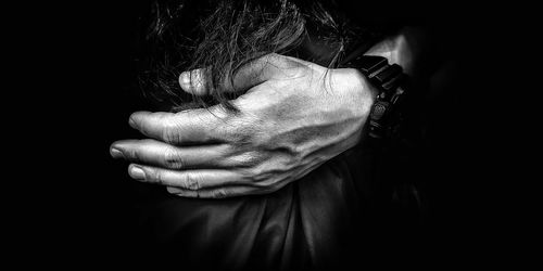 Close-up of hand holding hands over black background