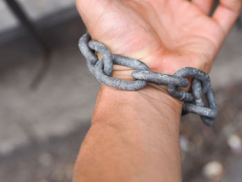 Cropped hand of person tied up with chain