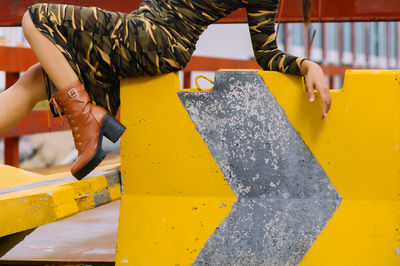 Low section of woman sitting on barricade