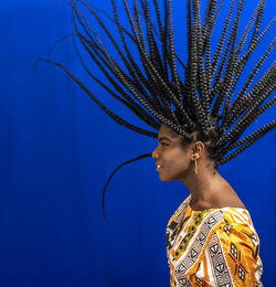 Young woman wearing colorful long clothes over blue background. natural expression.